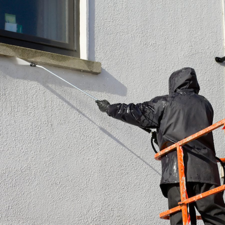 worker in cherry-piker washing a wall